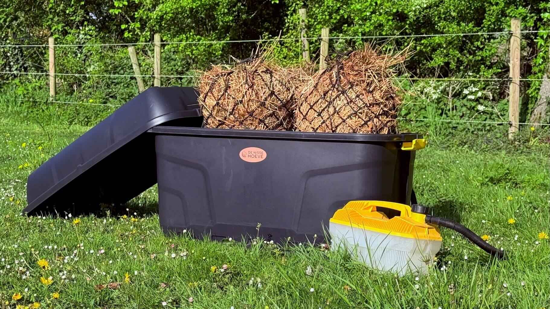 Zwarte hooistomer de krui met hooi op gras.