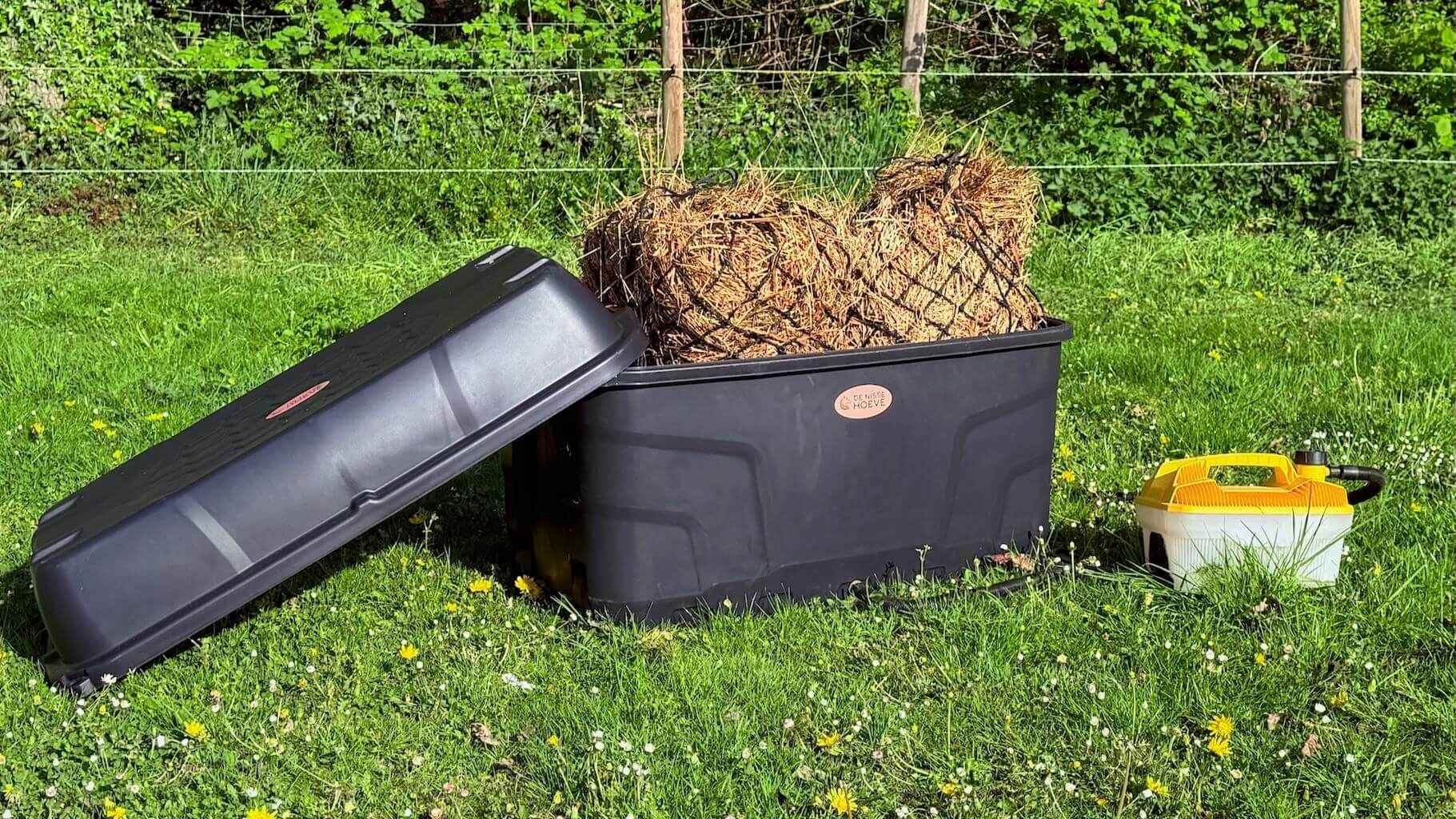 Hooistomer met hooi op grasveld.