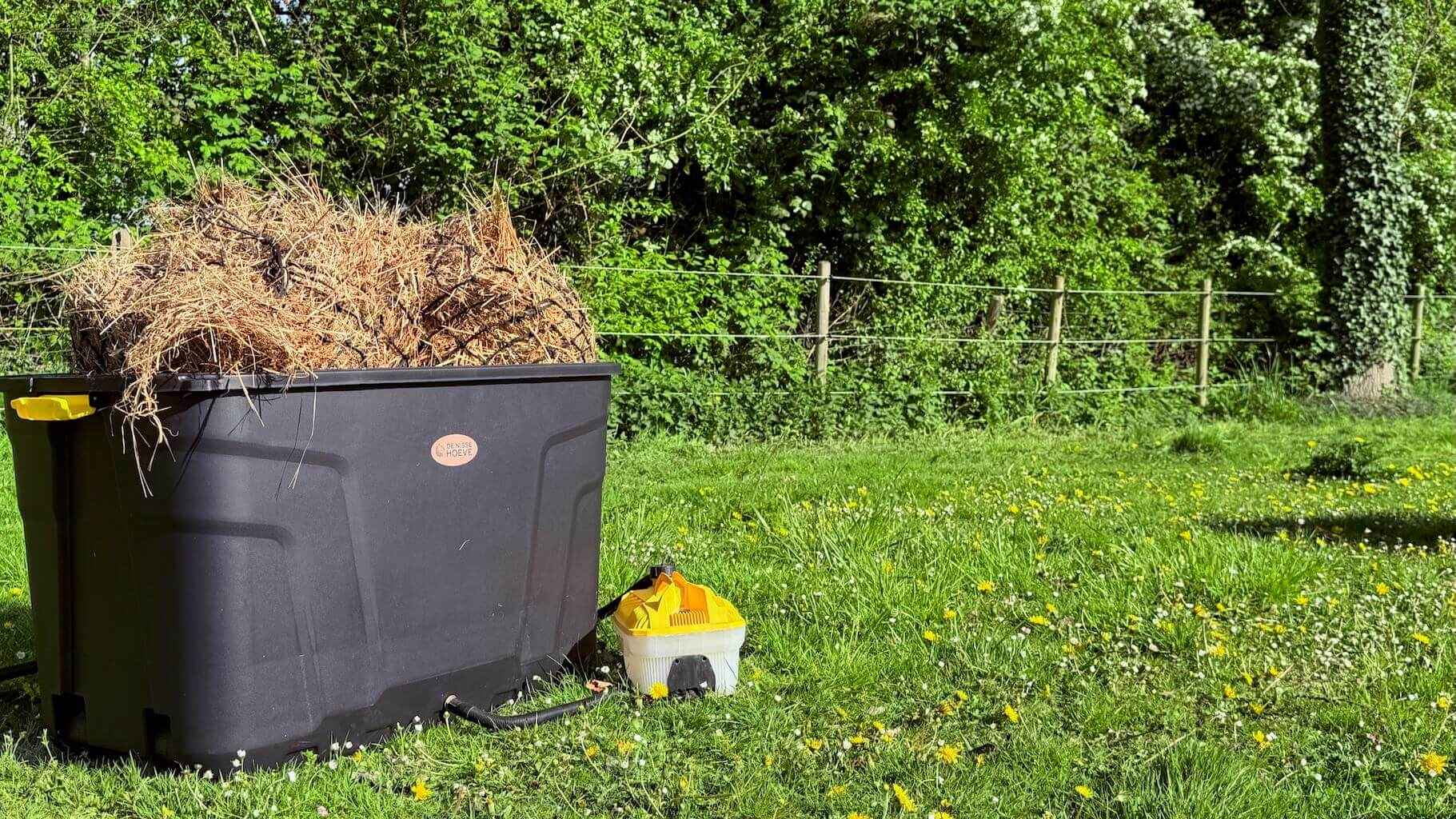 Hooistomer De Trog op het grasveld, met hooi en dampend stoom uit de slang voor gezonde paardenvoeding.