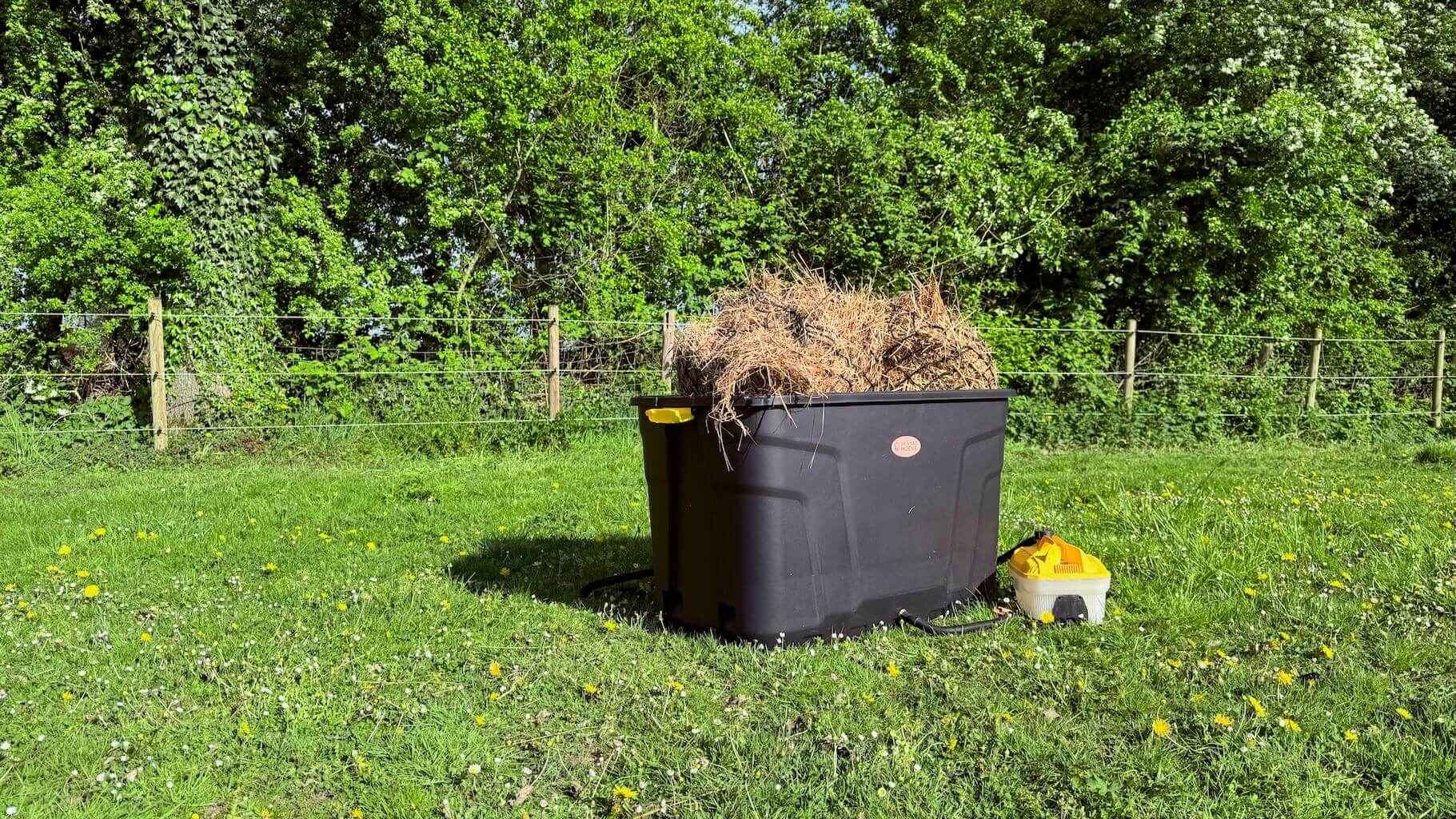 De Trog hooistomer buiten in het gras, gevuld met hooi en aangesloten op het stoomapparaat.