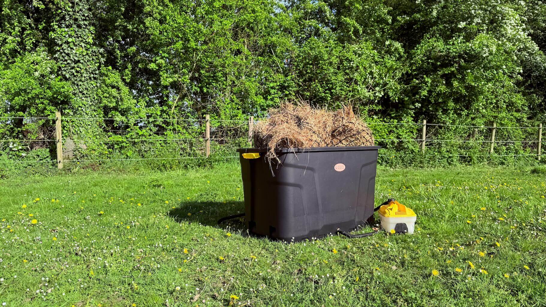 De Trog hooistomer buiten in het gras, gevuld met hooi en aangesloten op het stoomapparaat.