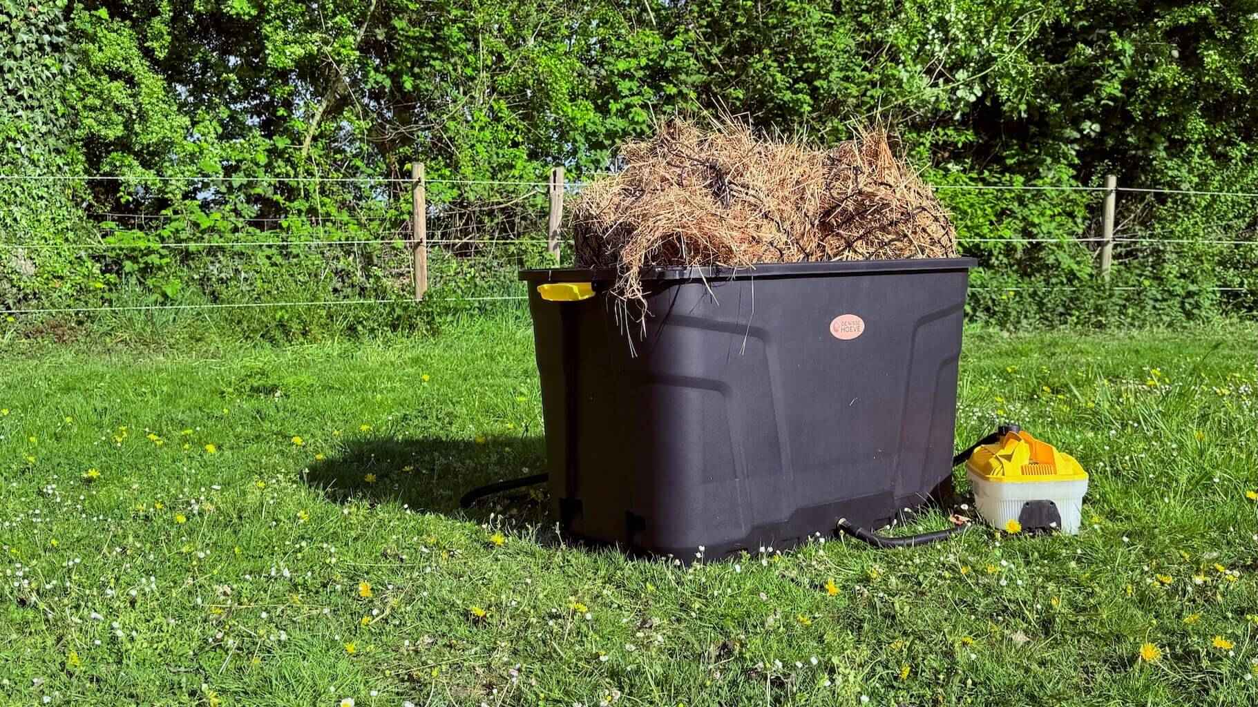 Hooistomer De Trog opgesteld in de wei, met stoomapparaat en hooi zichtbaar in de bak.