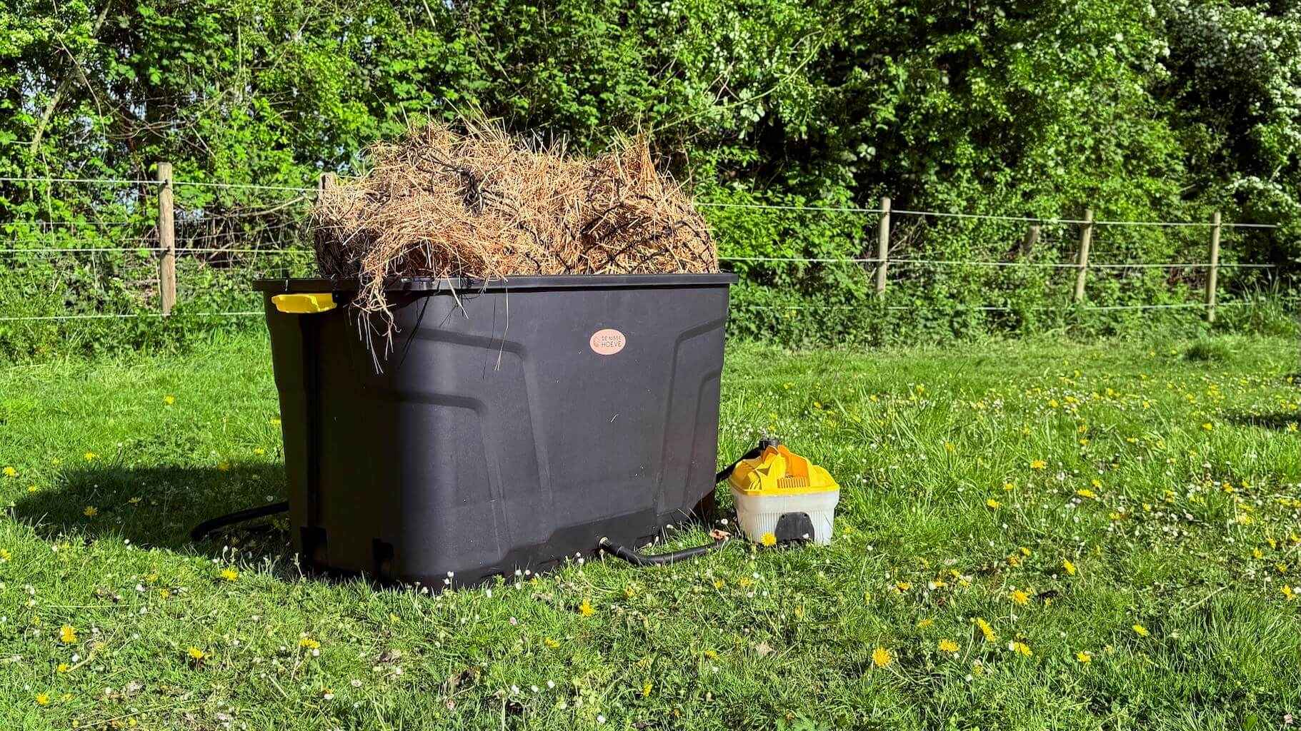 De Trog hooistomer in de wei, op het gras geplaatst met aangesloten stoomapparaat en zichtbaar hooi.