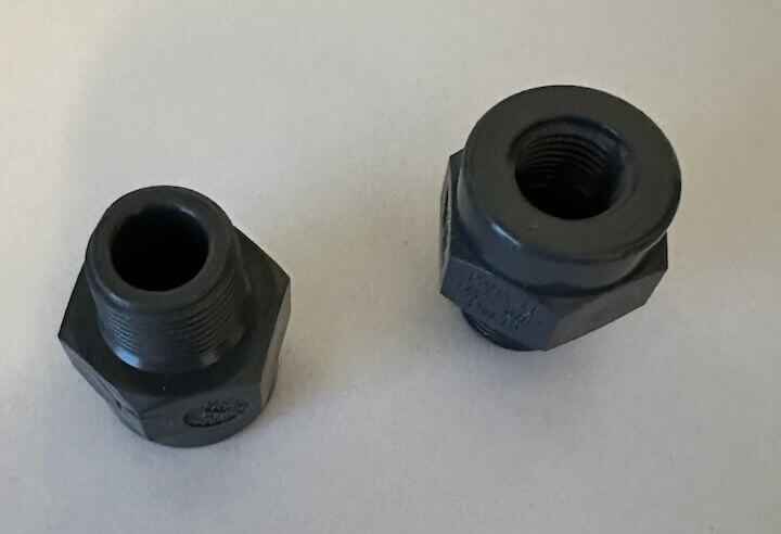 Twee zwarte kunststof schroefverbindingen op witte ondergrond.